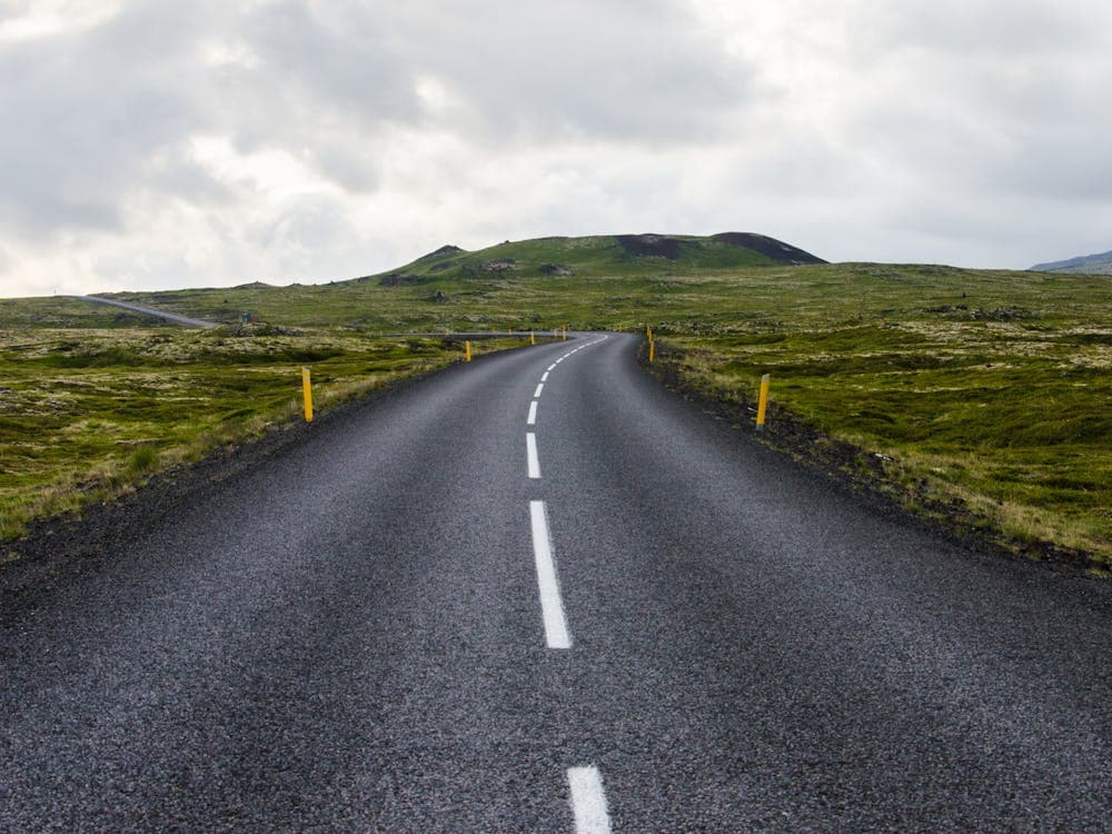 gray-concrete-road-towards-green-mountain